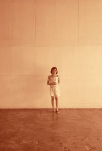 Young woman standing against wall