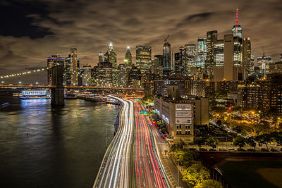 Illuminated bridge and buildings against sky at night