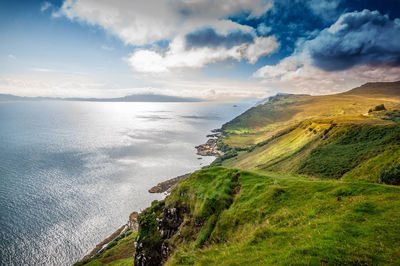 Scenic view of sea by cliff against sky