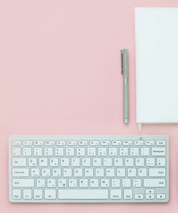 Directly above shot of book and pen by computer keyboard on table