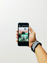 Cropped image of woman holding smart phone against white background
