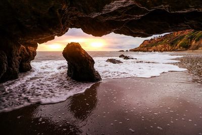 Rock formation on beach against sky