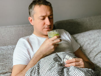 Young woman using mobile phone while lying on sofa at home