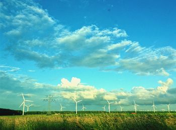 Windmill on field against blue sky