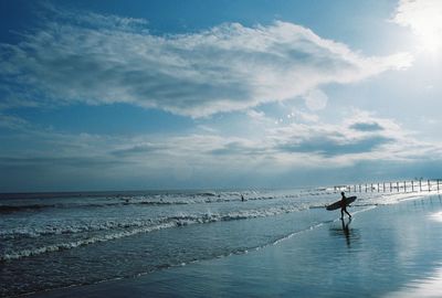 Man walking on beach against sky