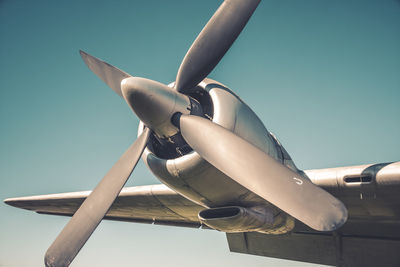 Low angle view of airplane flying against clear blue sky