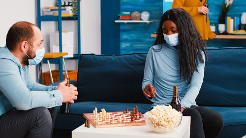 Man and woman wearing mask playing chess