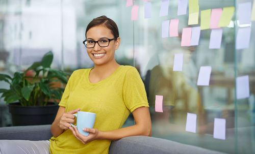 Happy businesswoman holding coffee cup in office