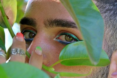 Close-up portrait of young man with green leaves