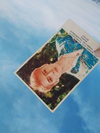 Low angle view of hand holding umbrella against blue sky