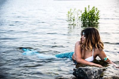Woman wearing mermaid costume while resting in sea