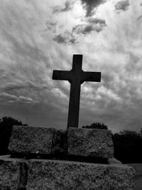 Low angle view of cross in cemetery against sky