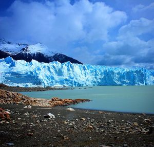 Scenic view of snow covered mountains against cloudy sky