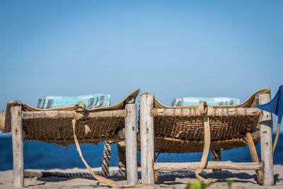 Camp beds on beach against clear blue sky