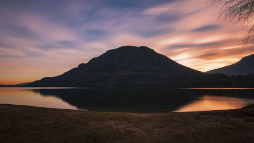 Scenic view of lake by mountains against sky during sunset