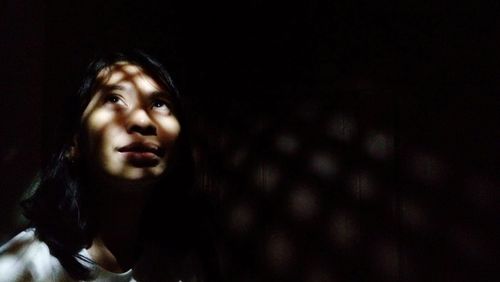 Woman looking up against wall in darkroom