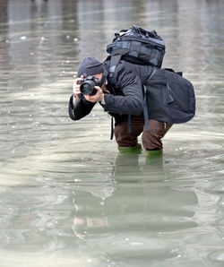 Man photographing in water filled walkway during flood