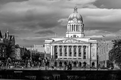 Buildings in city against cloudy sky