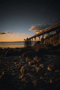 Bridge over river against sky during sunset