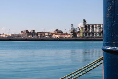 Scenic view of river by buildings against clear blue sky