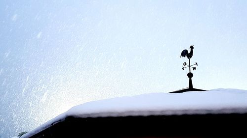 Low angle view of weather vane against cloudy sky