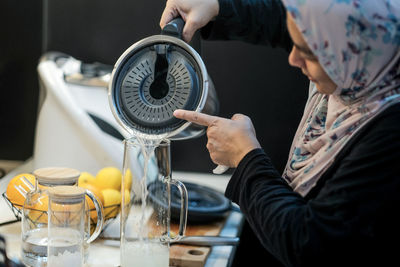 A woman in hijab is preparing lime juice in the kitchen