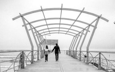 Rear view full length of mother and daughter on pier at beach