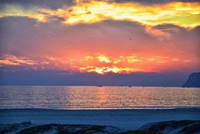 Scenic view of sea against dramatic sky during sunset