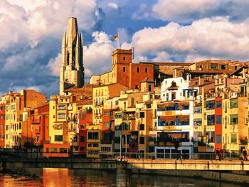 Buildings in girona city against cloudy sky