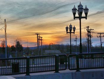 Silhouette of railing against cloudy sky at sunset