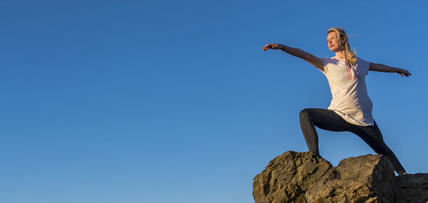 Low angle view of woman against clear blue sky