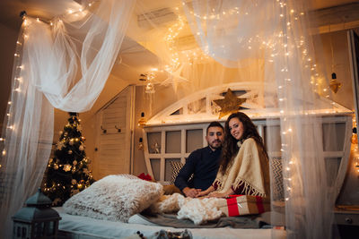 Woman sitting by illuminated christmas lights