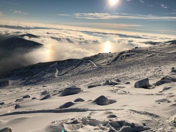 Scenic view of snow covered mountains against bright sun