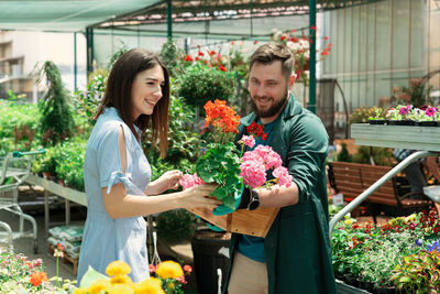 Farmer giving flowering plant to customer