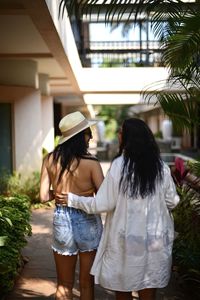 Side view of woman standing against palm tree