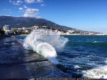 Sea waves splashing on mountain against blue sky