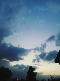 Low angle view of silhouette trees against blue sky