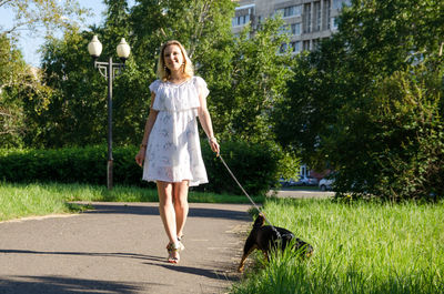 Beautiful blonde girl with a cute dog for a walk.