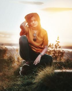 Young woman looking away while sitting on land