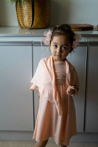 A little girl is standing in a beautiful dress with hair accessories. pretend play at home.