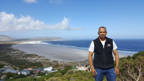 Portrait of man standing at beach against sky