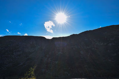 Low angle view of mountains against bright sun