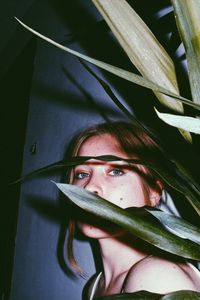 Close-up portrait of young woman with blue eyes by plants