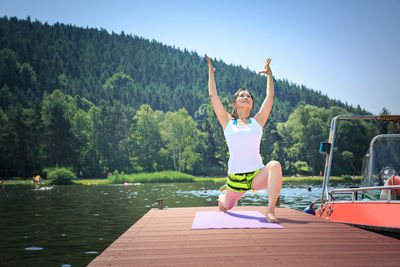 Mature woman exercising on pier over river