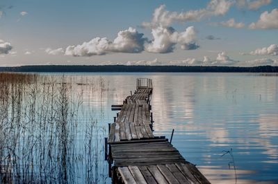 Wooden pier on lake against sky