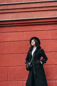 Portrait of smiling woman standing against brick wall