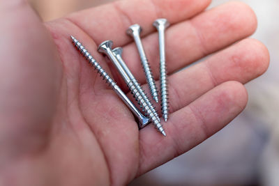 Close-up of hand holding screws