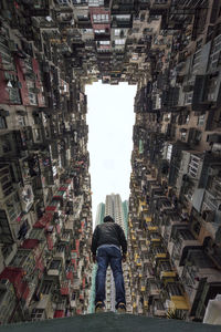 Rear view of man standing amidst buildings in city