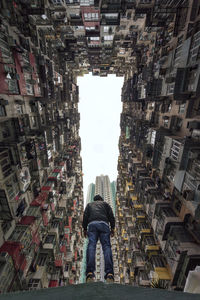 Low angle view of man standing amidst buildings in city