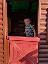 Portrait of boy smiling while standing house entrance